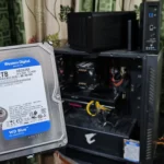 Người cầm ổ cứng HDD trước dàn máy tính và hai thiết bị NAS TerraMaster