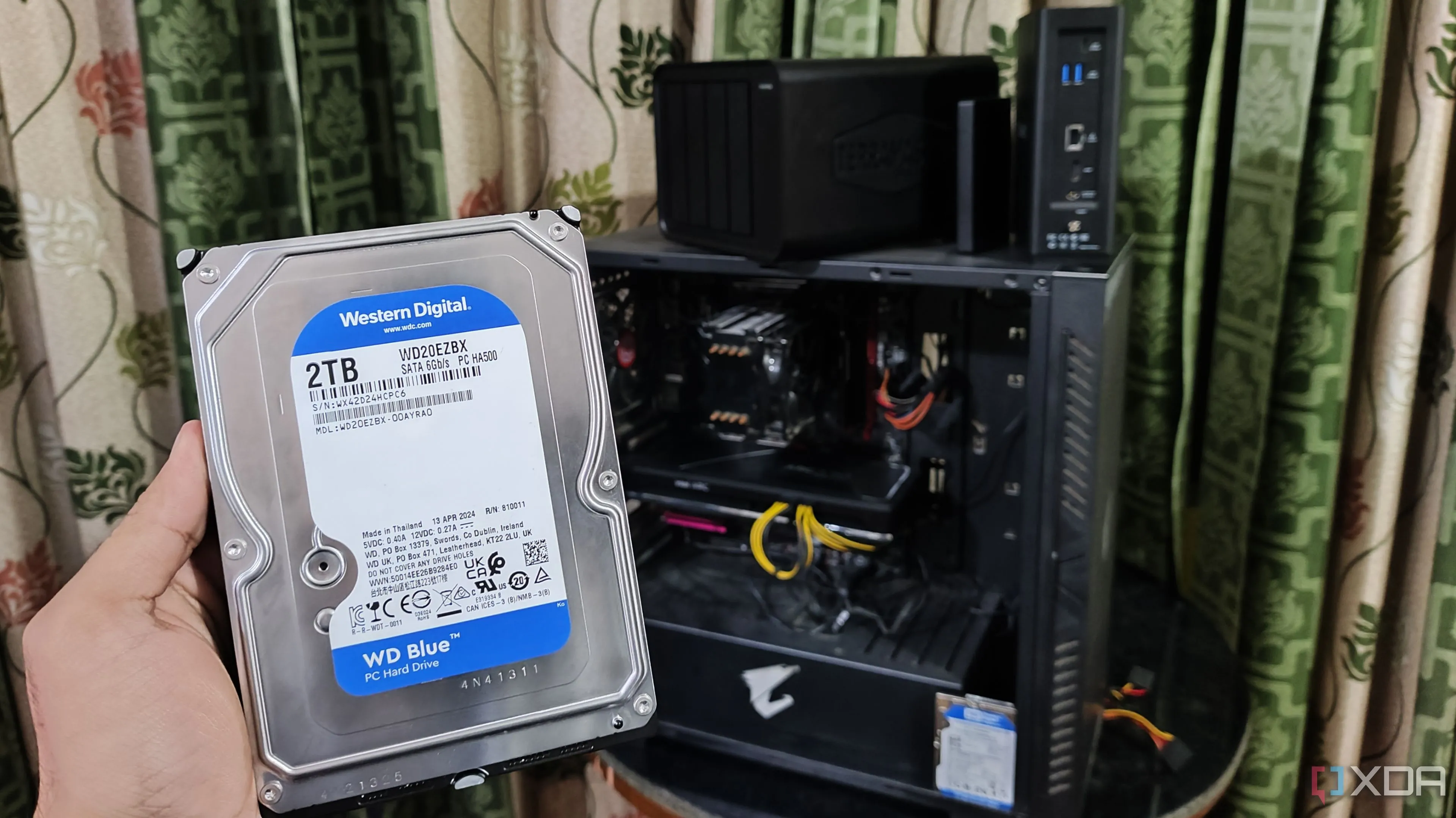 Người cầm ổ cứng HDD trước dàn máy tính và hai thiết bị NAS TerraMaster