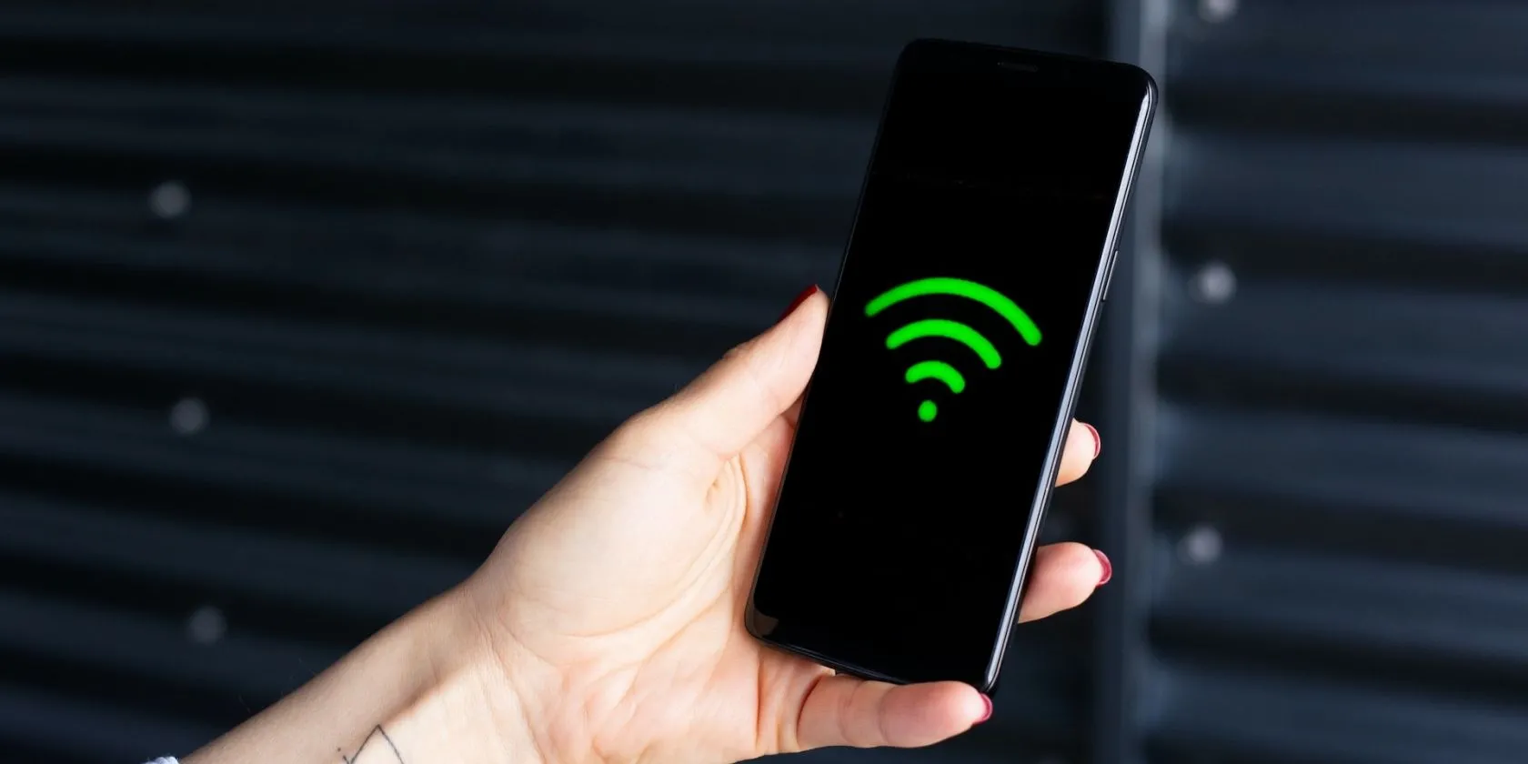 Bàn tay cầm điện thoại thông minh hiển thị biểu tượng Wi-Fi, minh họa việc quản lý kết nối hotspot.
