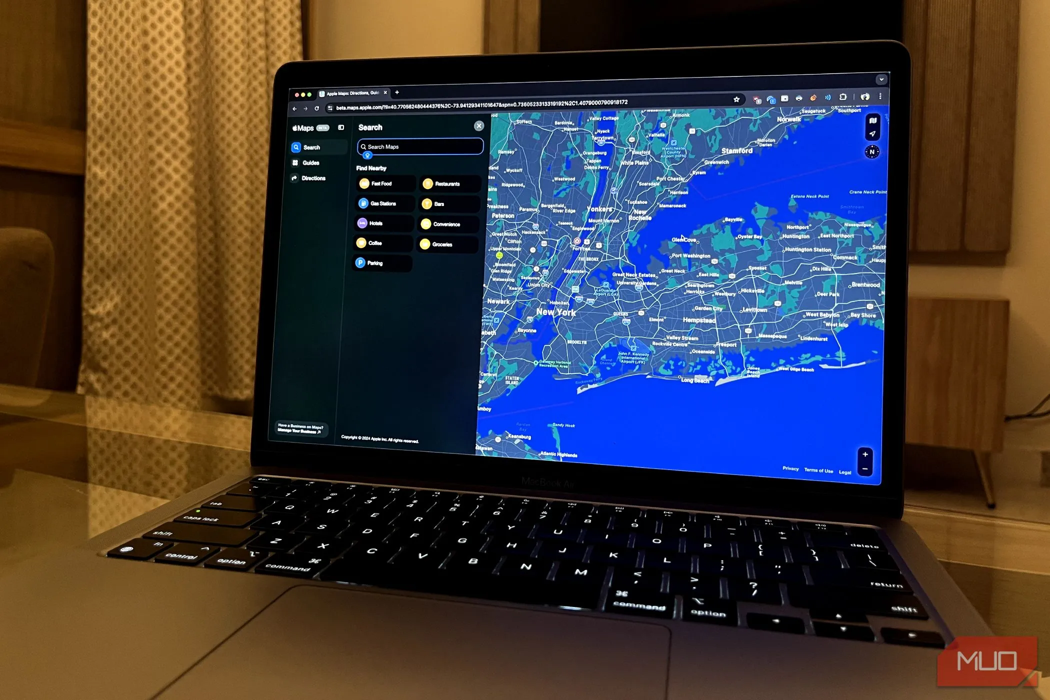 Giao diện Apple Maps đang mở trên trình duyệt Chrome trên MacBook, phía sau là màn hình TV.