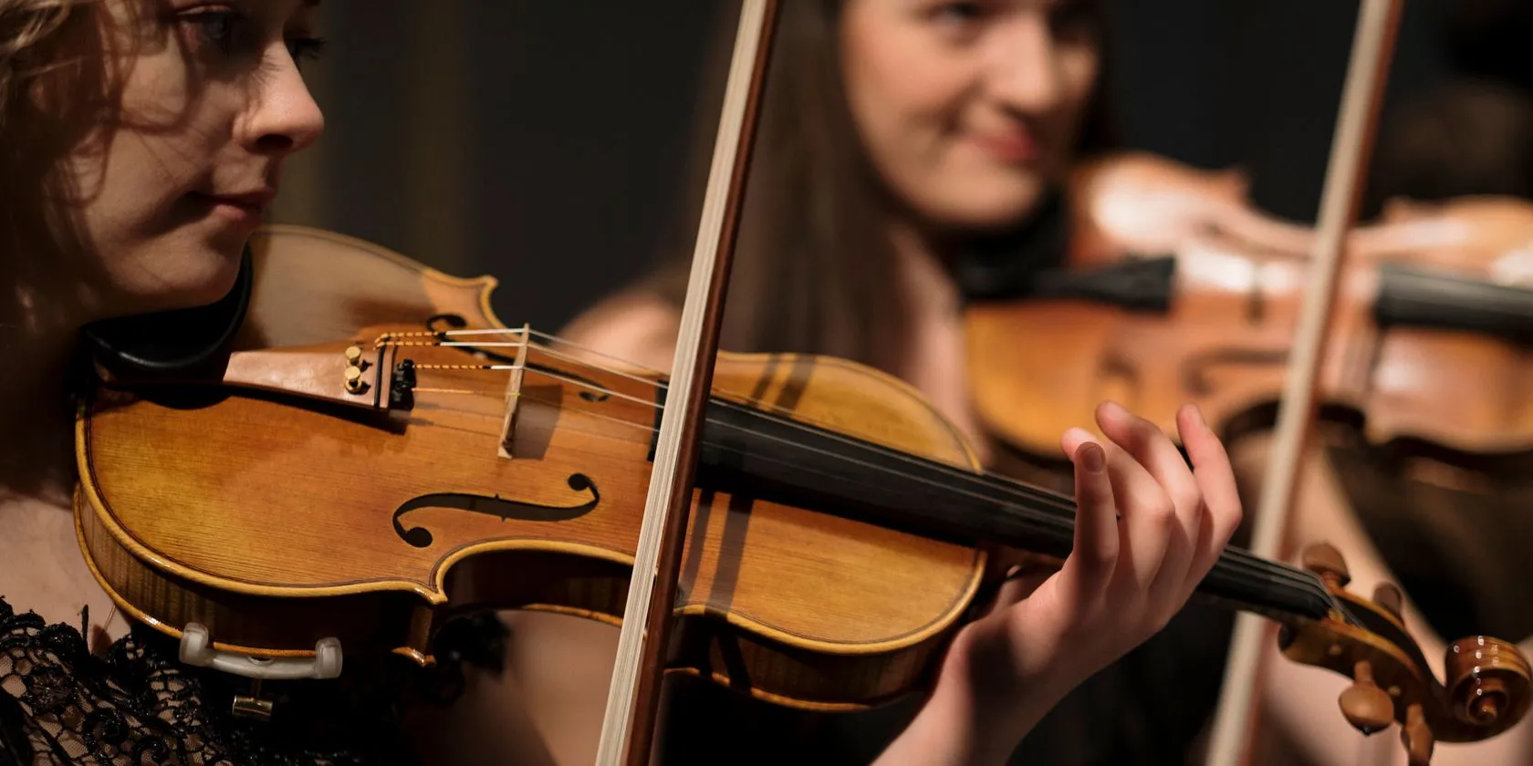 Nữ nghệ sĩ chơi violin trong dàn nhạc giao hưởng, đại diện cho kho tàng âm nhạc cổ điển trên Apple Music Classical.