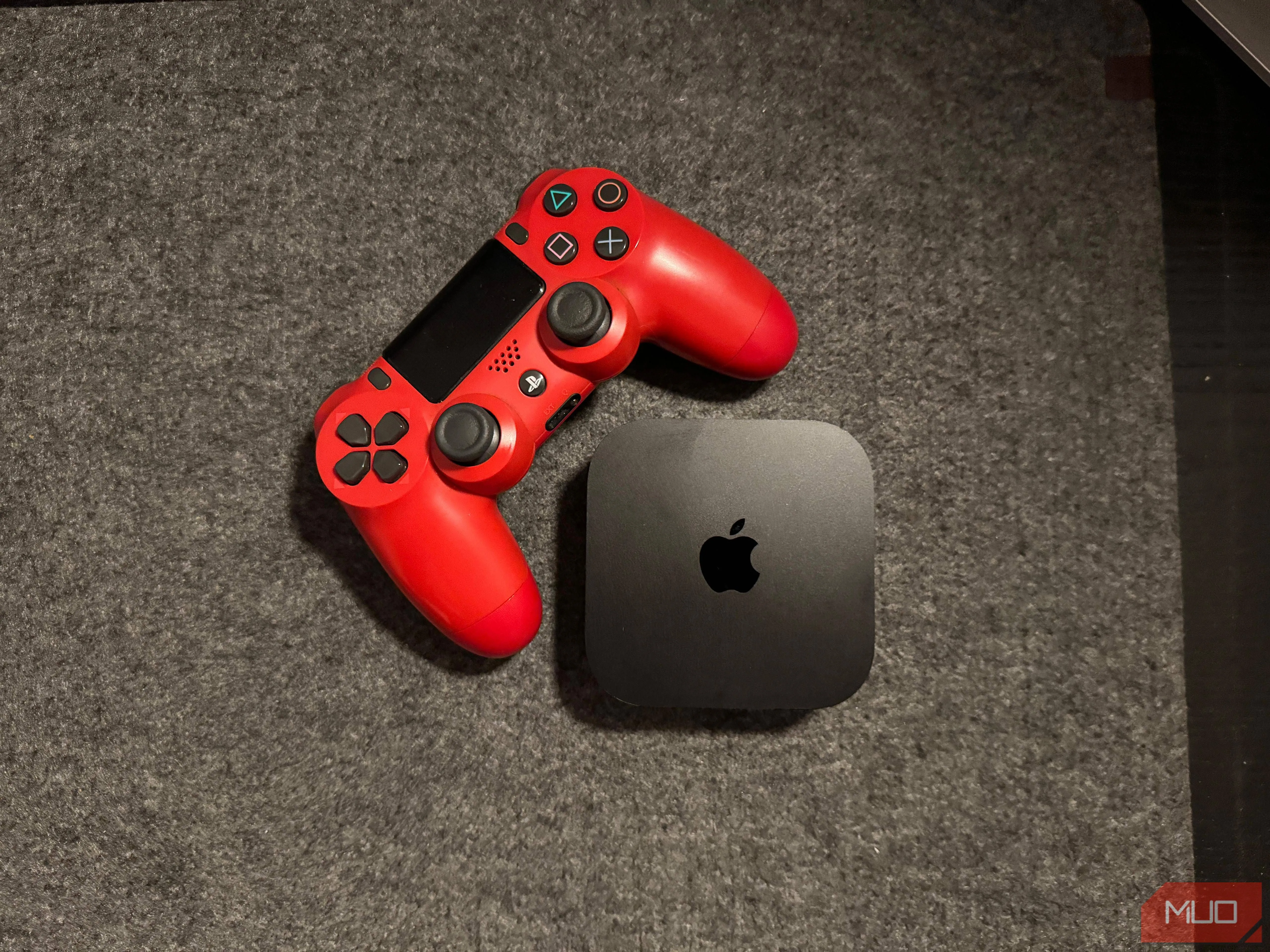 Apple TV 4K đặt cạnh tay cầm PS4, minh họa khả năng chơi game nhẹ và kết nối tay cầm dễ dàng.
