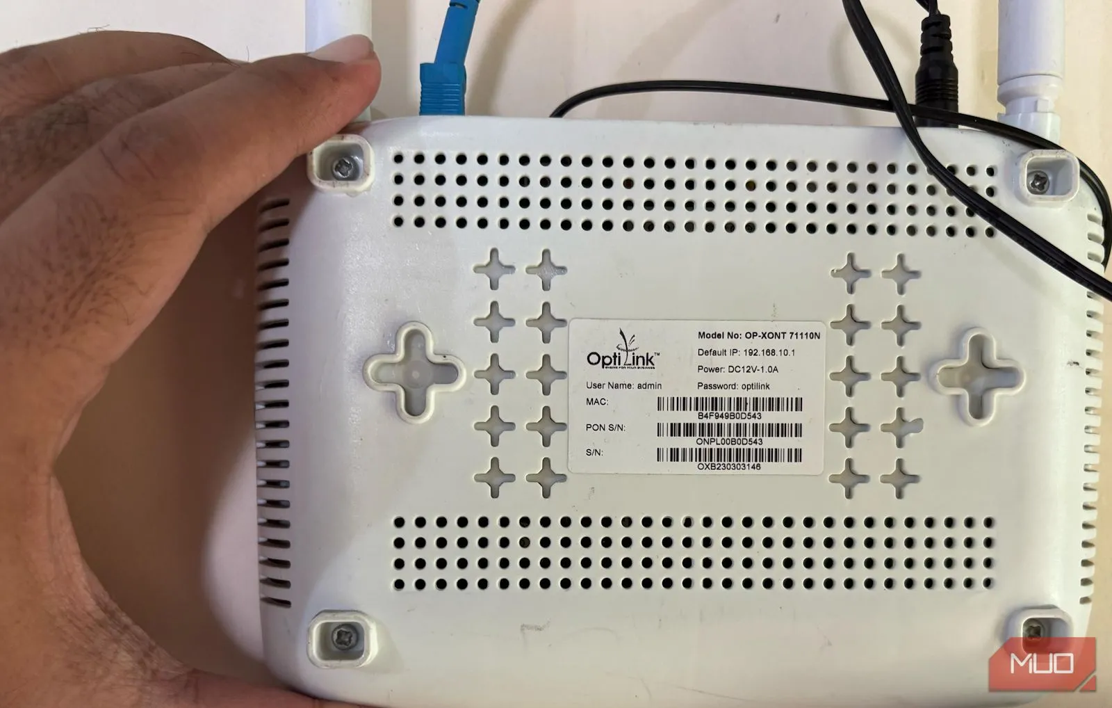 Bàn tay cầm router Wi-Fi và chỉ vào mặt sau của thiết bị