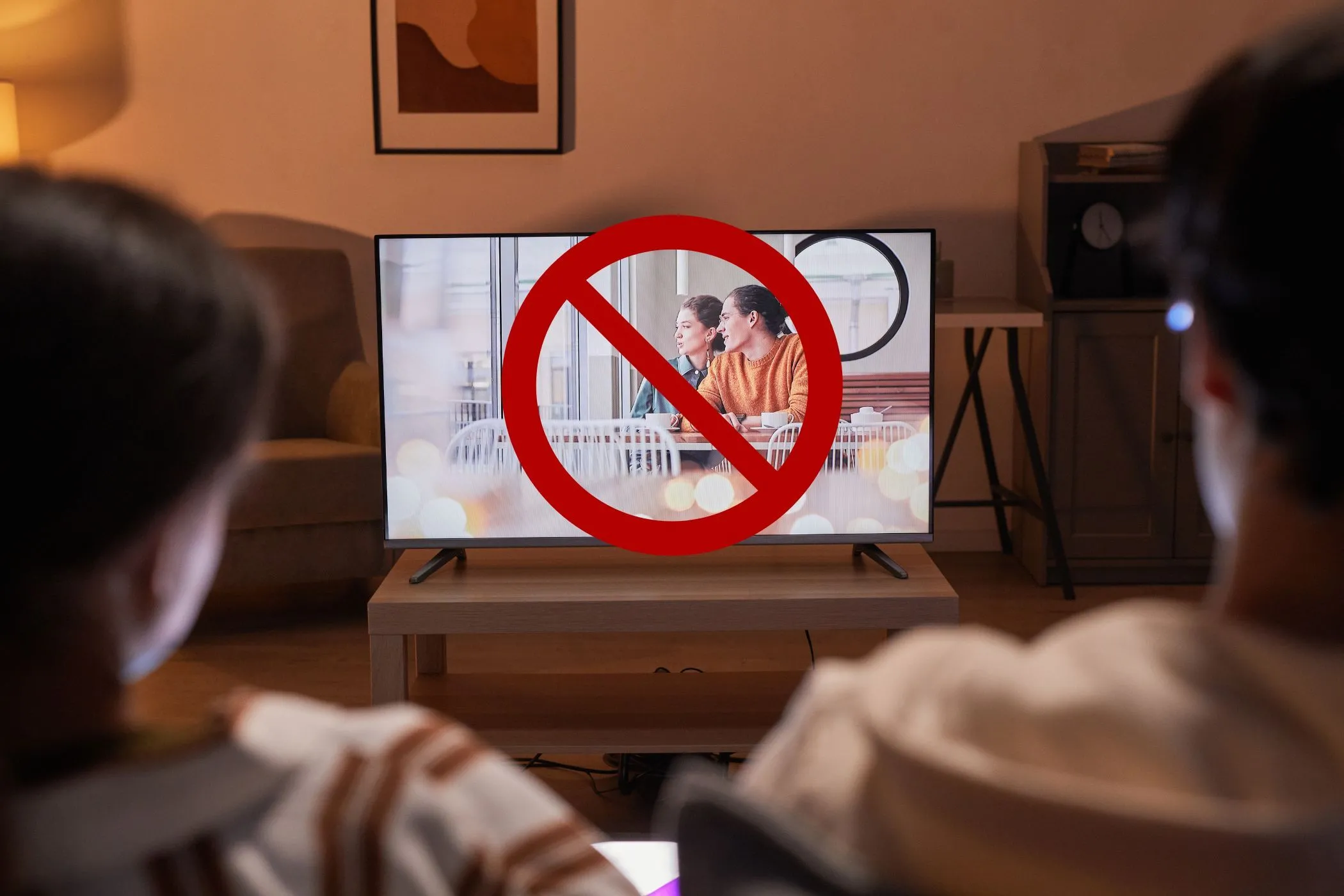 Cặp đôi đang xem TV với biểu tượng vòng tròn gạch chéo trên màn hình, tượng trưng cho việc vô hiệu hóa các tính năng theo dõi và đề xuất AI trên Smart TV để bảo vệ quyền riêng tư.