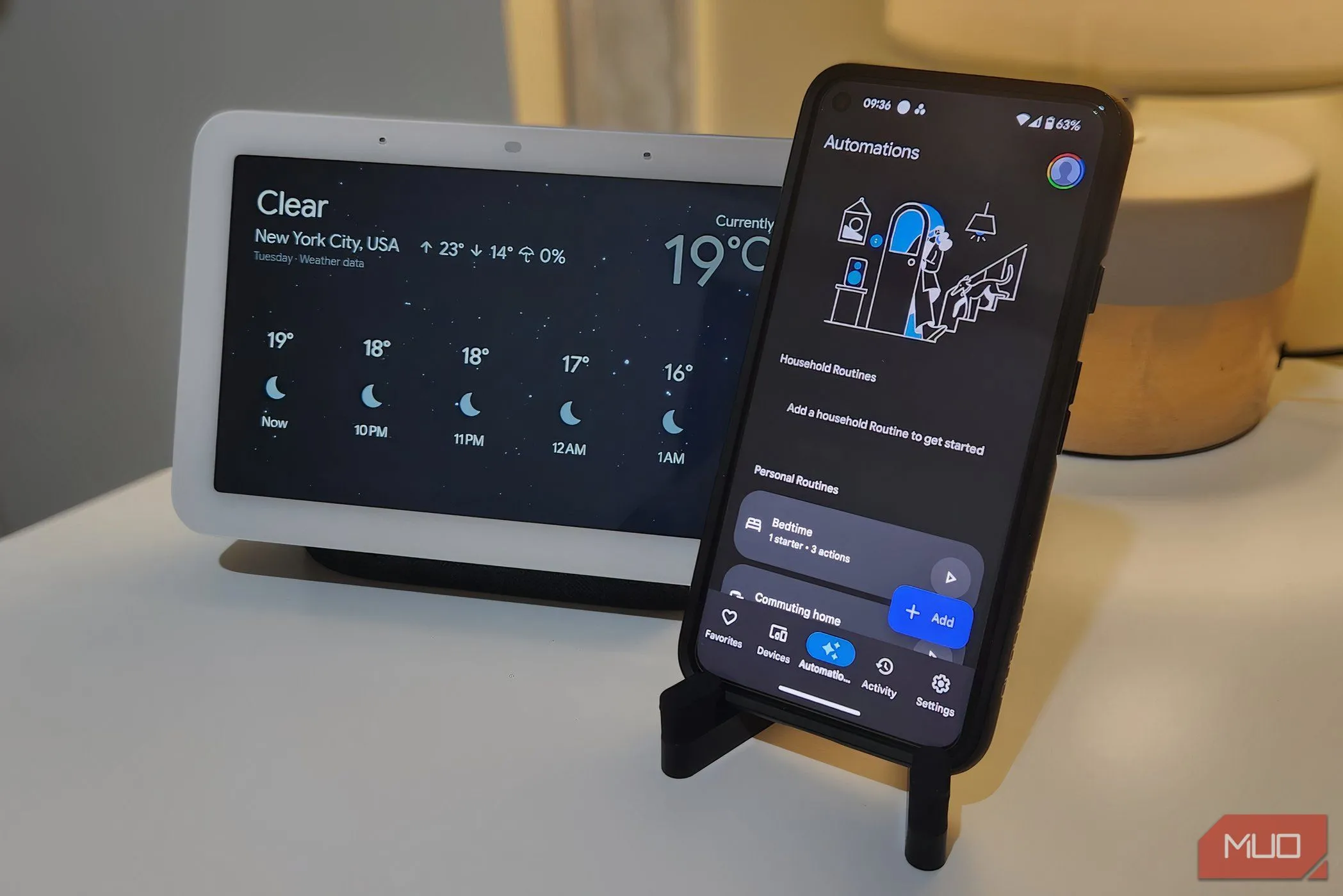 Điện thoại hiển thị menu Google Home Automations với Nest Hub phía sau