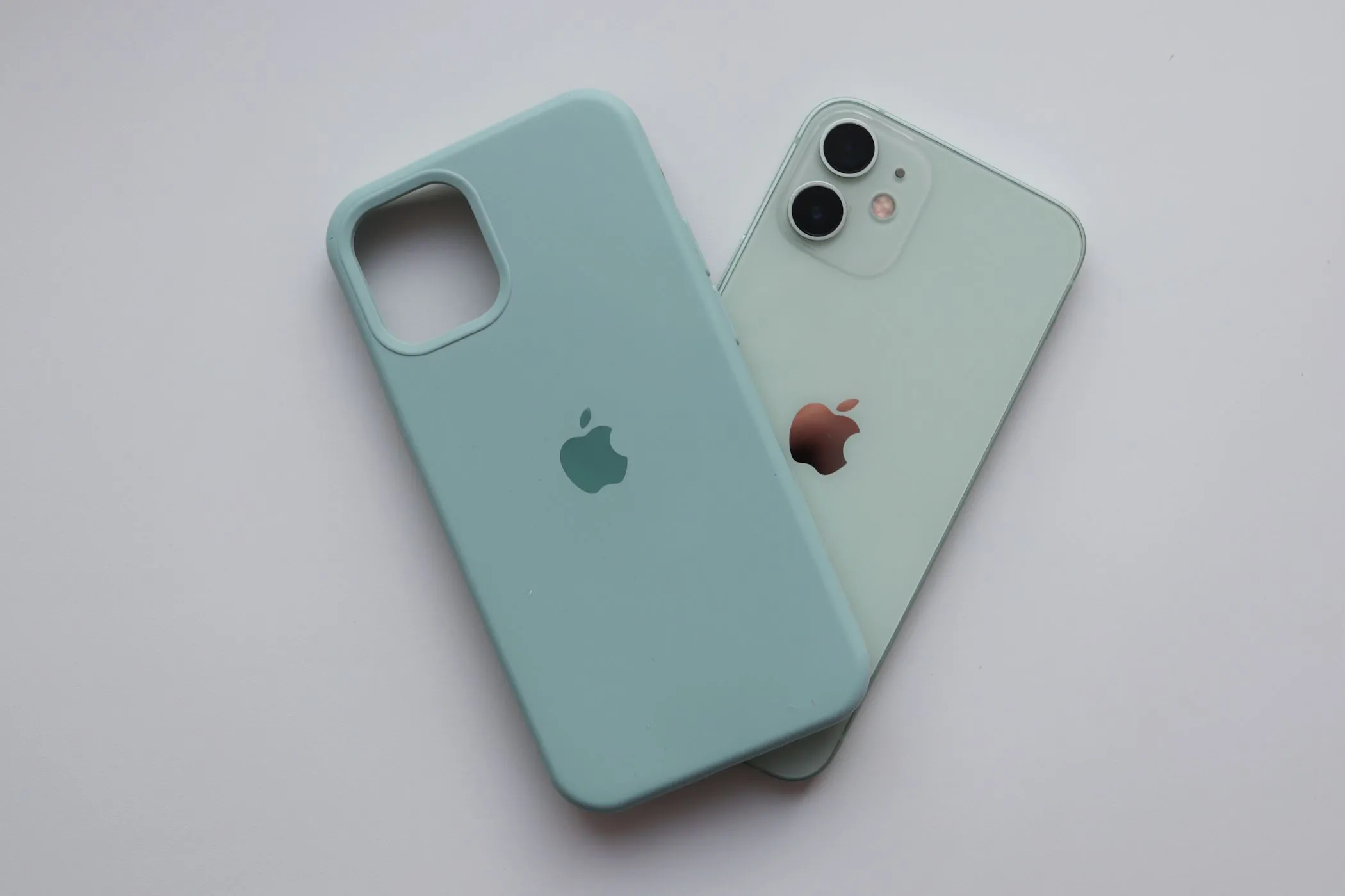 iPhone 12 màu xanh pastel đặt cạnh ốp lưng silicon, minh họa cho điện thoại iPhone đời cũ.