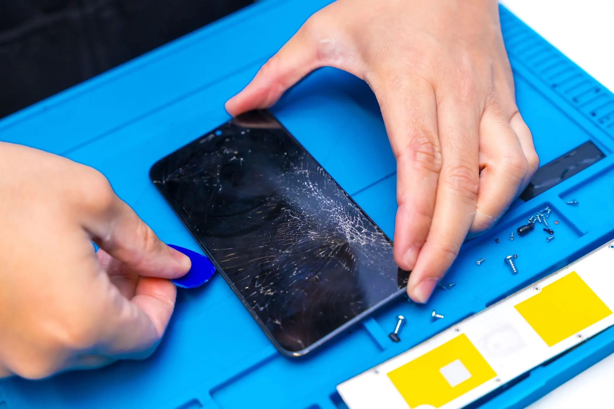 Kỹ thuật viên đang tháo dỡ smartphone để sửa chữa tại trung tâm bảo hành ủy quyền