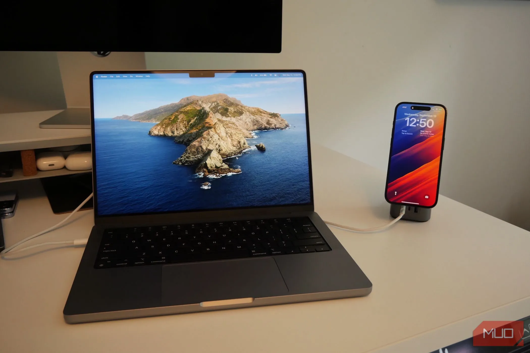 MacBook Pro và iPhone đang sạc trên bàn làm việc