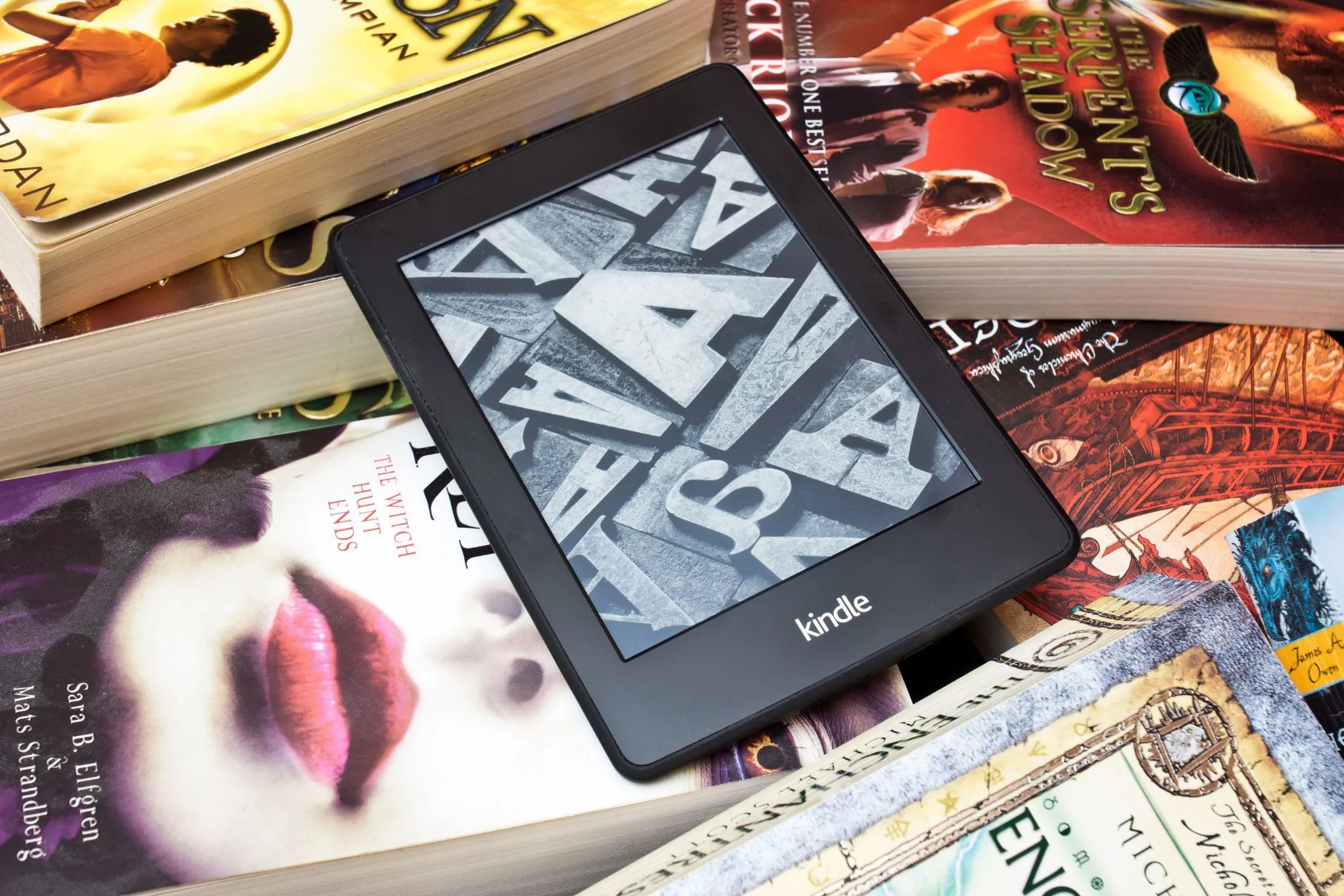 Máy đọc sách Kindle nằm trên chồng sách giấy, minh họa sự chuyển dịch từ bản in sang sách điện tử