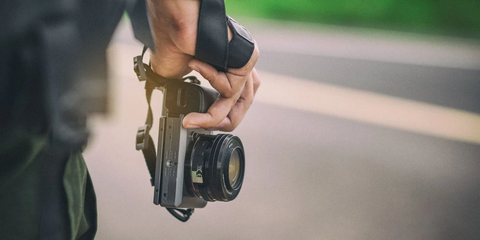 Người du lịch cầm máy ảnh mirrorless trên tay, với cảnh quan tự nhiên phía sau, thể hiện sự trở lại của nhiếp ảnh chuyên dụng.