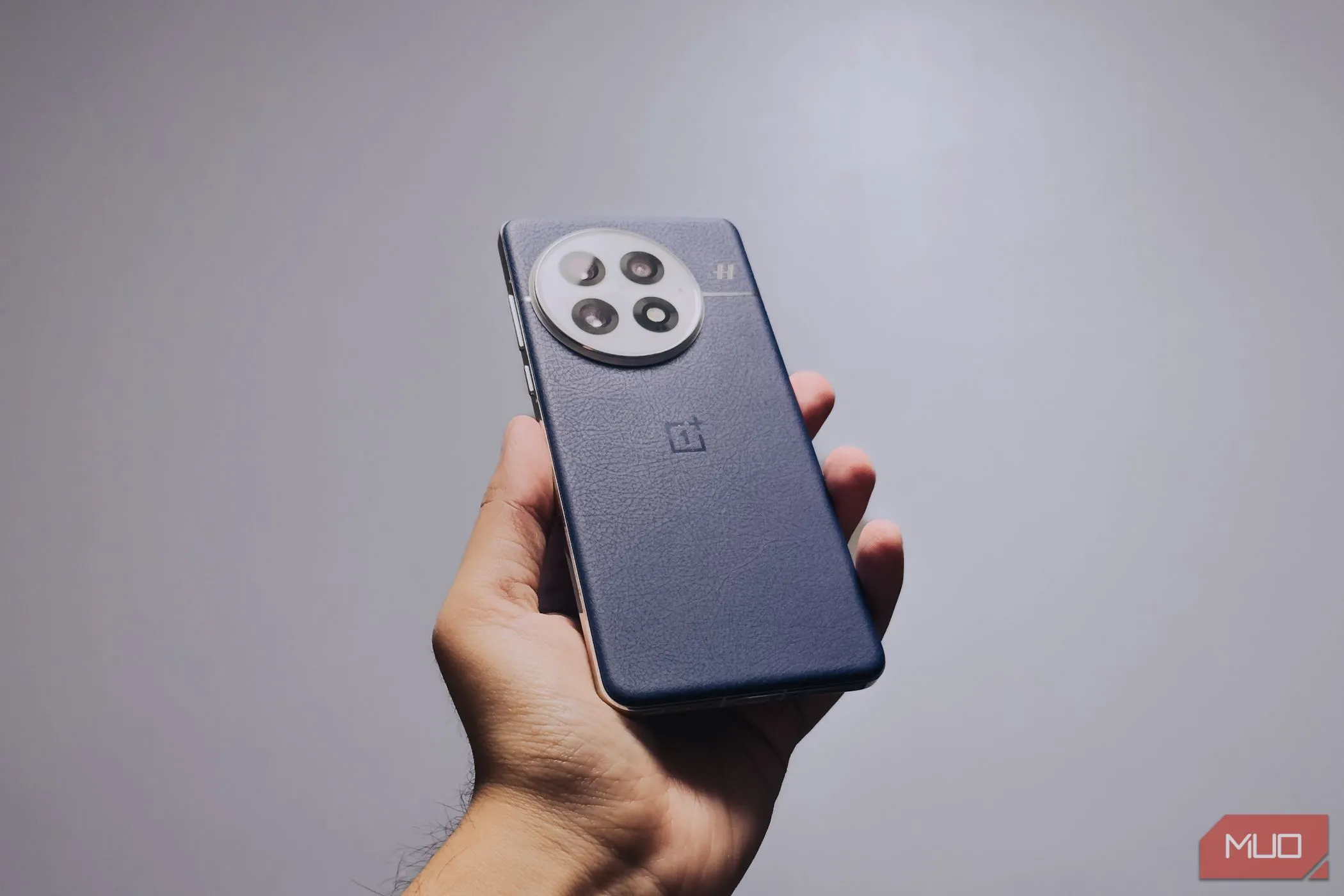 Người dùng đang cầm điện thoại OnePlus 13 màu xanh Midnight Ocean, cho thấy thiết kế mặt lưng da và độ bám tốt của máy