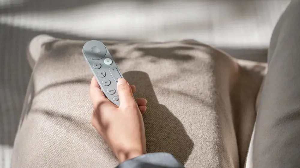 Người dùng đang cầm điều khiển Google TV Streamer, minh họa thiết kế cải tiến và nút âm lượng mới