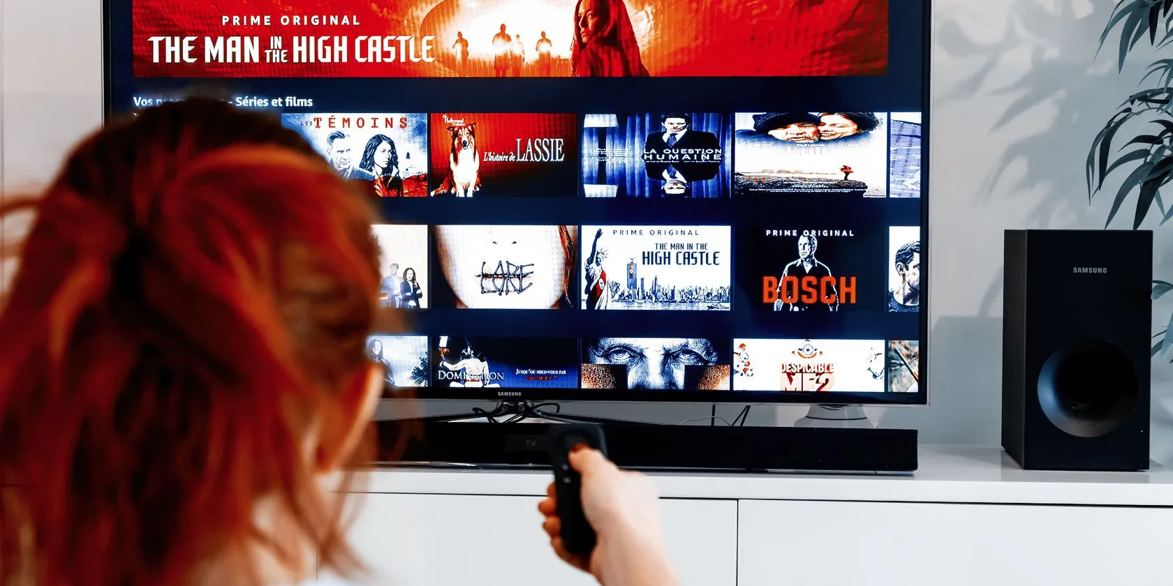 Người phụ nữ cầm điều khiển chỉ vào màn hình TV hiển thị Prime Video của Amazon