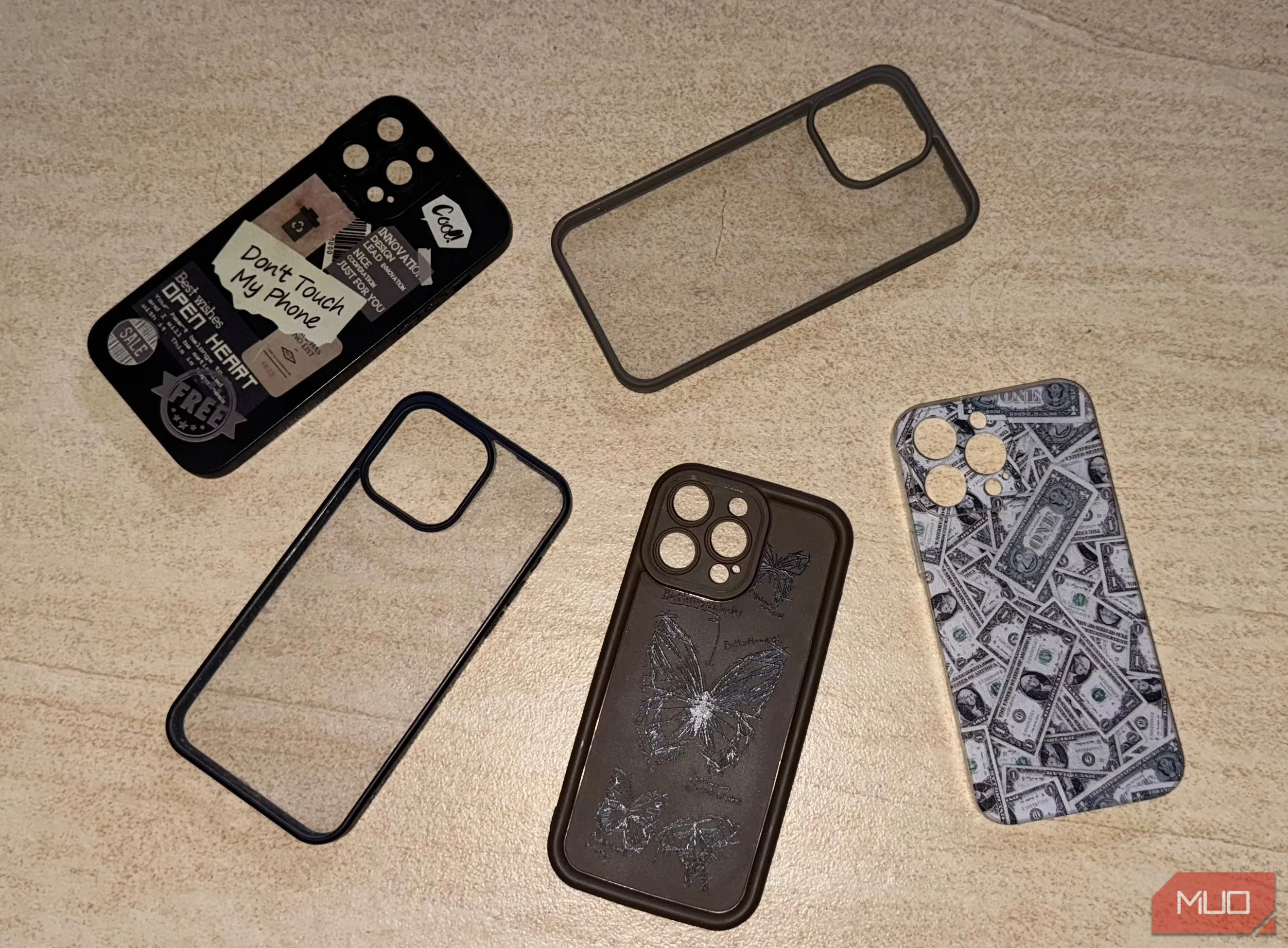 Nhiều ốp lưng bảo vệ cho iPhone 15 Pro Max đặt trên sàn nhà, minh họa cách điện thoại siêu mỏng có thể bù đắp độ dày khi sử dụng ốp.