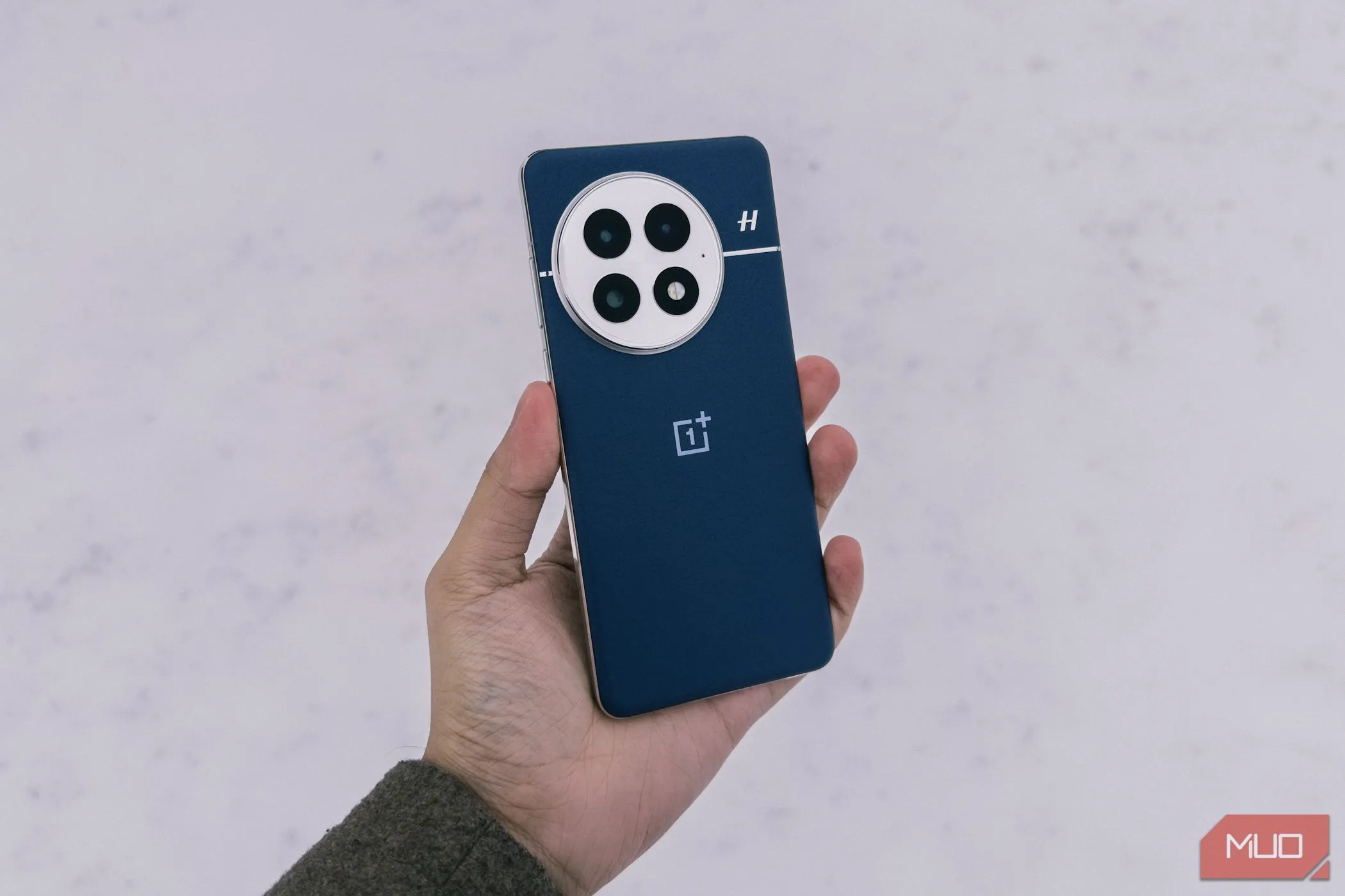 OnePlus 13 màu xanh Midnight Ocean được cầm trên tay giữa khung cảnh tuyết trắng, tượng trưng cho độ bền và khả năng thích nghi