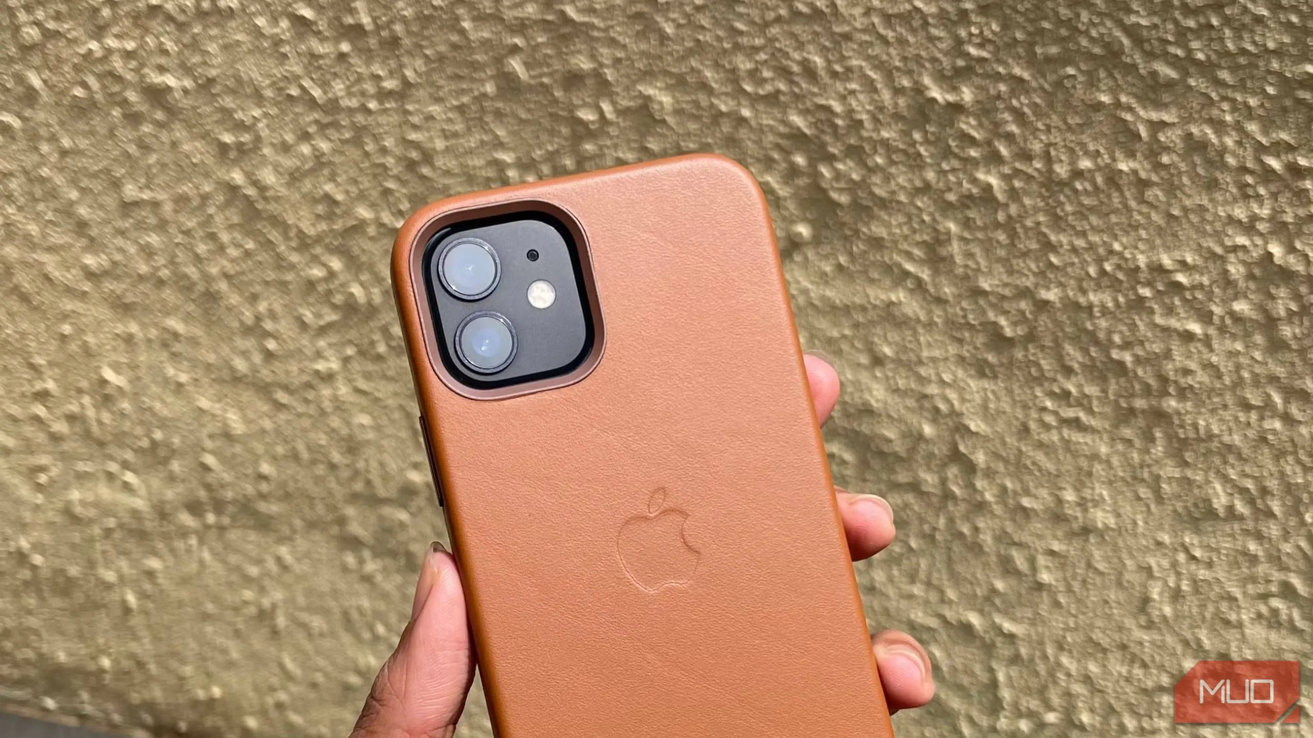 Ốp lưng da màu nâu nhạt của iPhone 12 được cầm trong tay, thể hiện vẻ đẹp và chất liệu cao cấp của da thật.