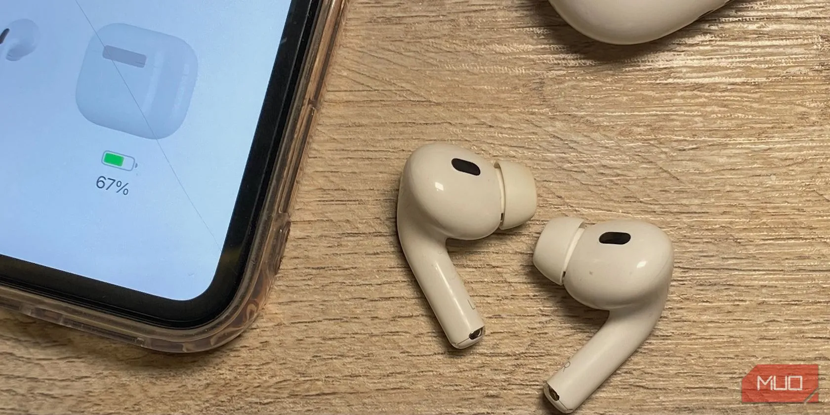 Tai nghe AirPods và iPhone đặt trên bàn gỗ, minh họa sự khác biệt về chiều dài thân giữa các thế hệ AirPods in-ear.