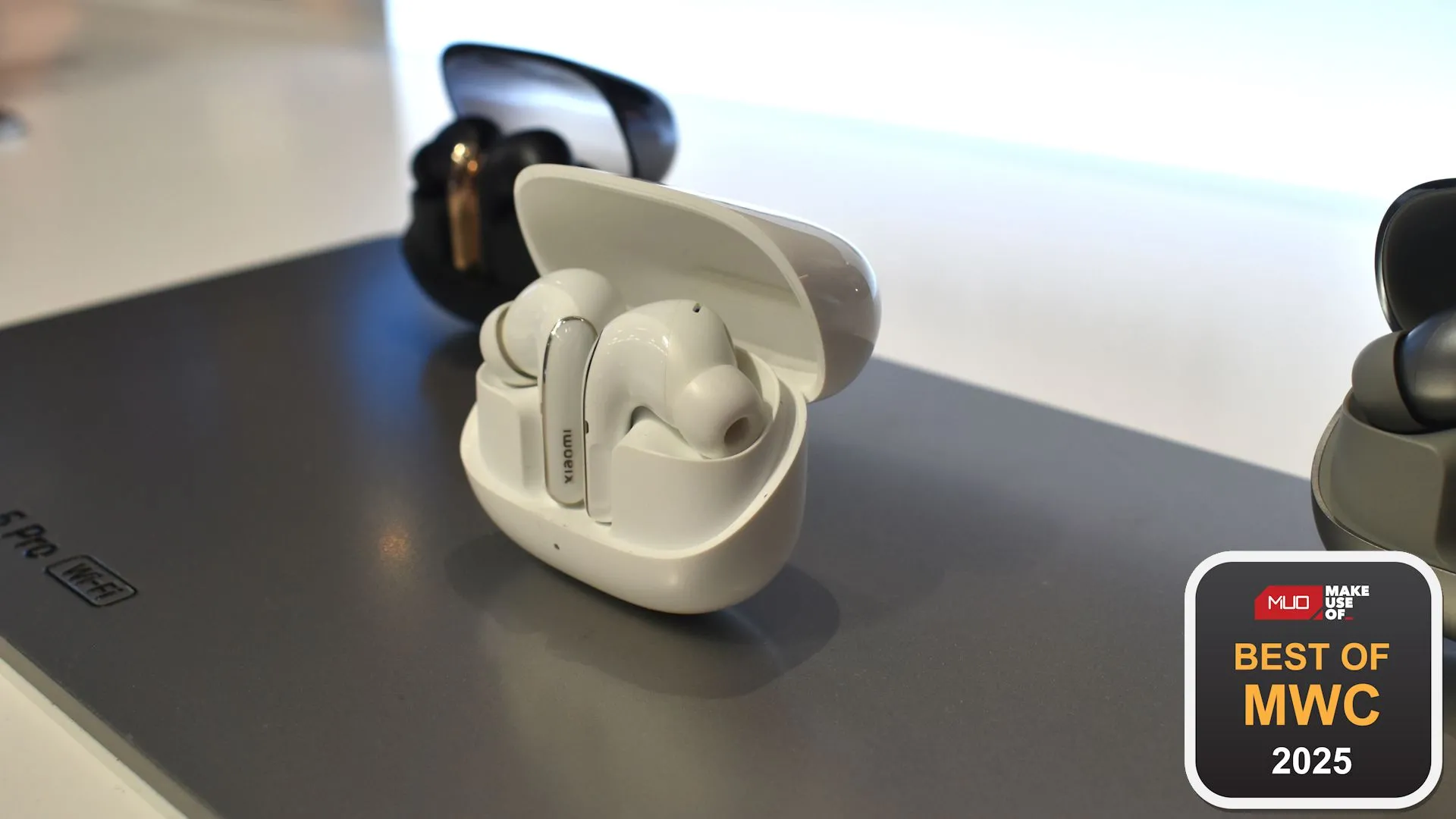 Tai nghe Xiaomi Buds 5 Pro Wi-Fi màu trắng với hộp sạc đang được trưng bày tại sự kiện MWC 2025.