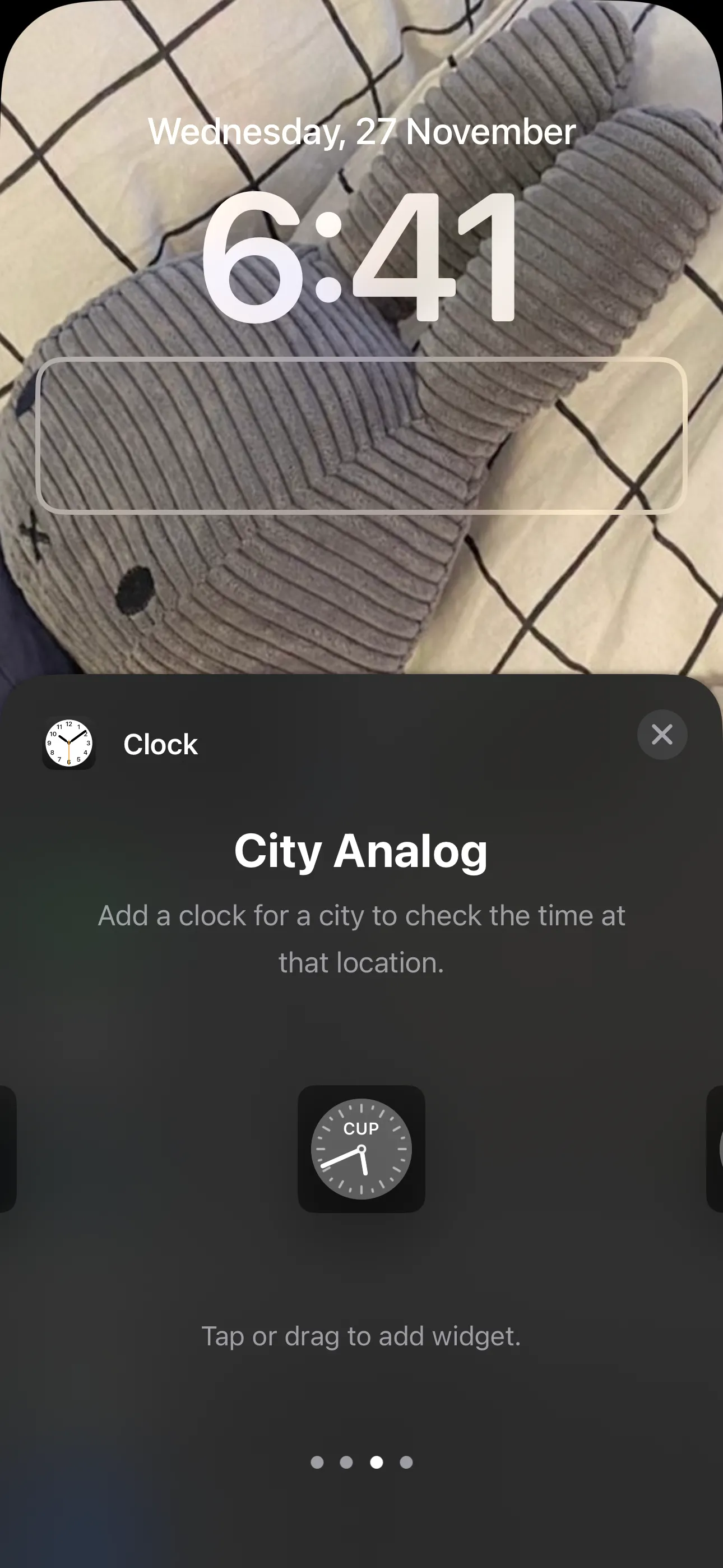 Widget đồng hồ kim thành phố hiển thị múi giờ trên màn hình khóa iPhone.